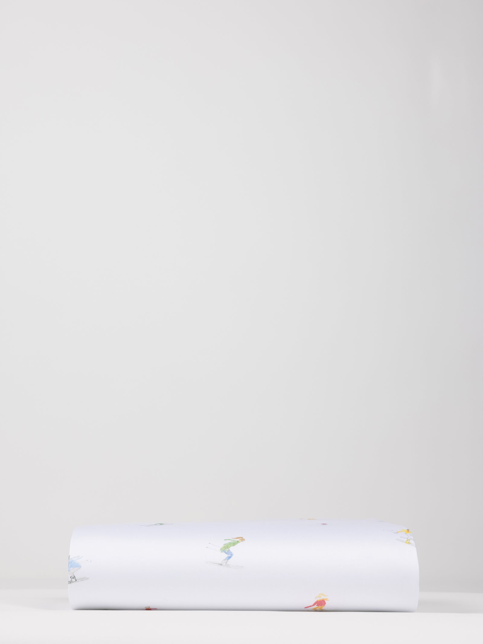 A neatly folded Bamboo Duvet Cover from Cozy Earth is laid flat against a plain, light gray background. The cover is predominantly white with small, colorful illustrations or designs scattered across its surface. 