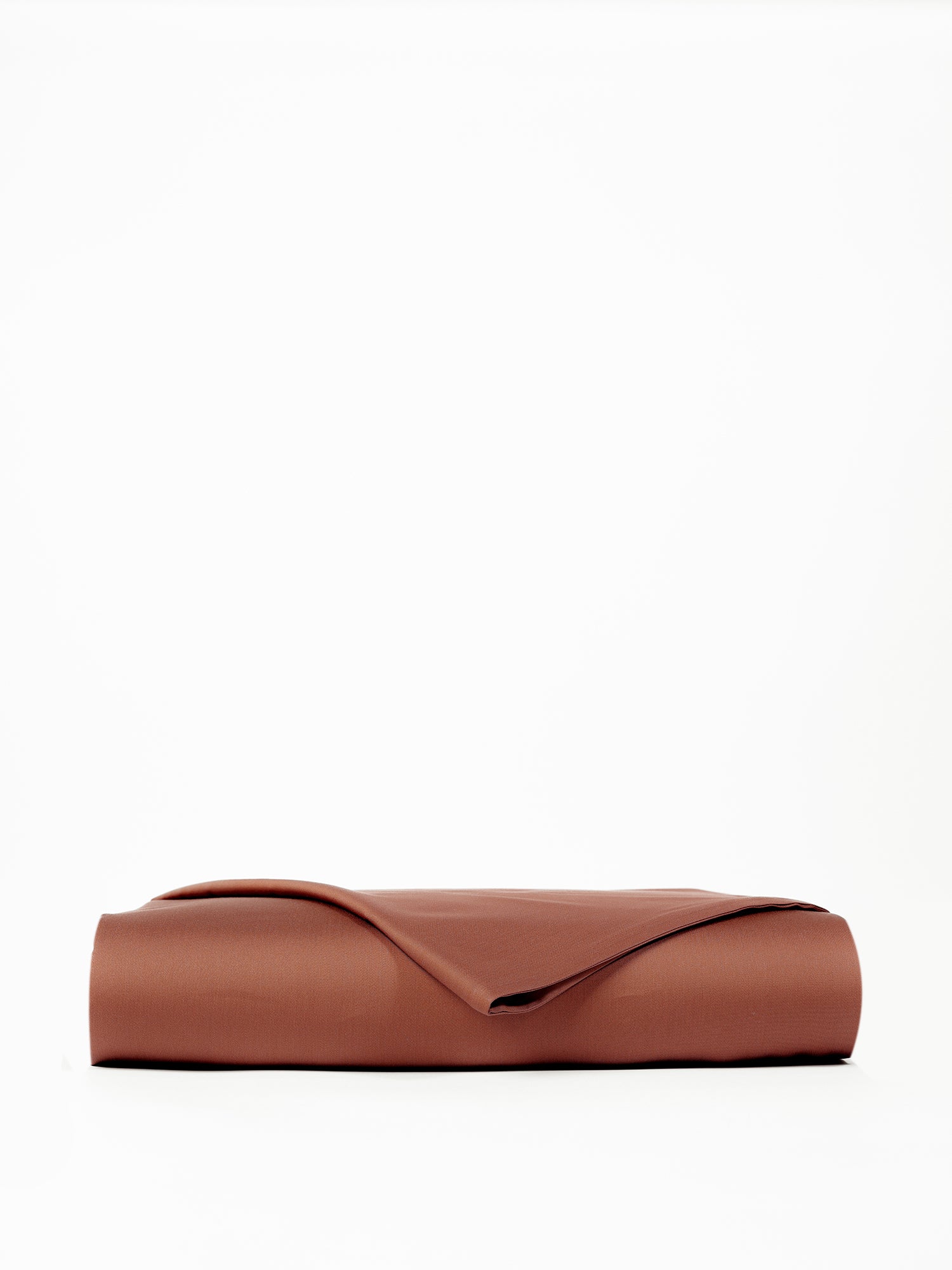 A neatly folded, rust-colored Bamboo Flat Sheet from Cozy Earth lies flat against a white background. The smooth fabric has a soft, cozy appearance, and one corner of the sheet is slightly lifted, revealing a glimpse of the inner side. |Color:Terra