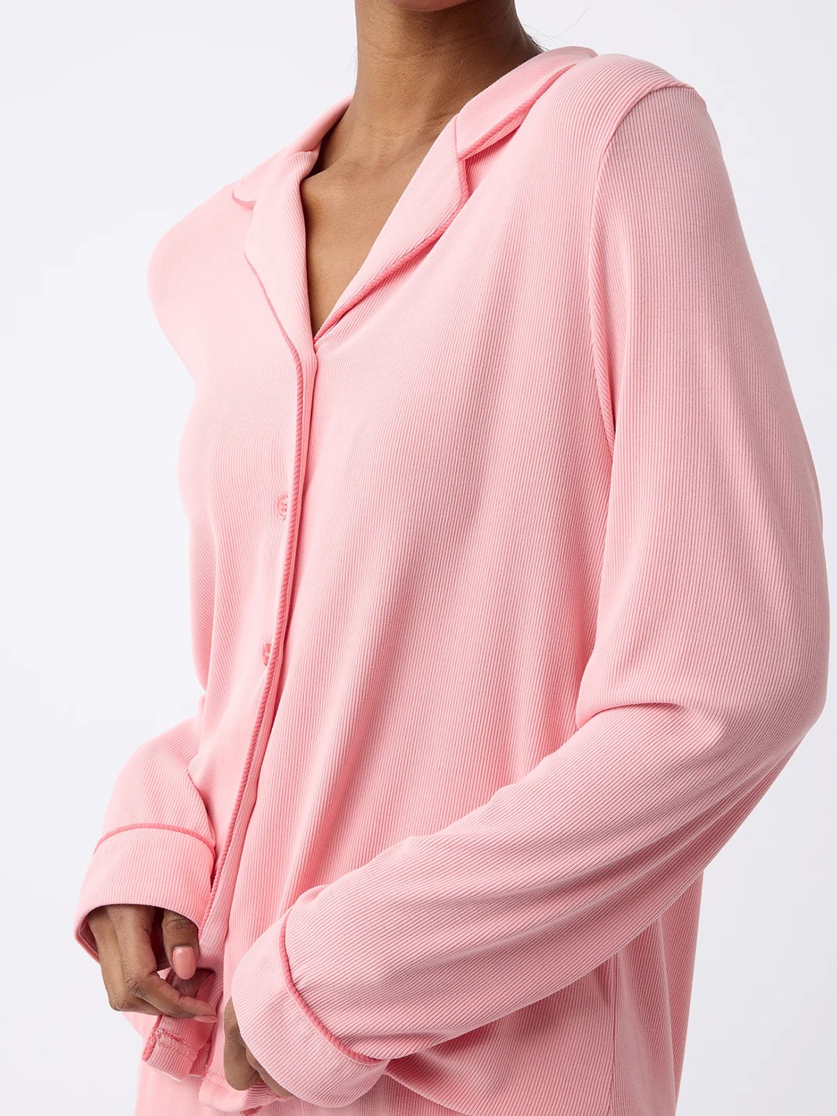 A woman is shown from the chest up, wearing Cozy Earth's Women's Bamboo Rib Knit Classic Long Sleeve Pajama Top in pink with a collar against a plain white background. |Color:Tulip