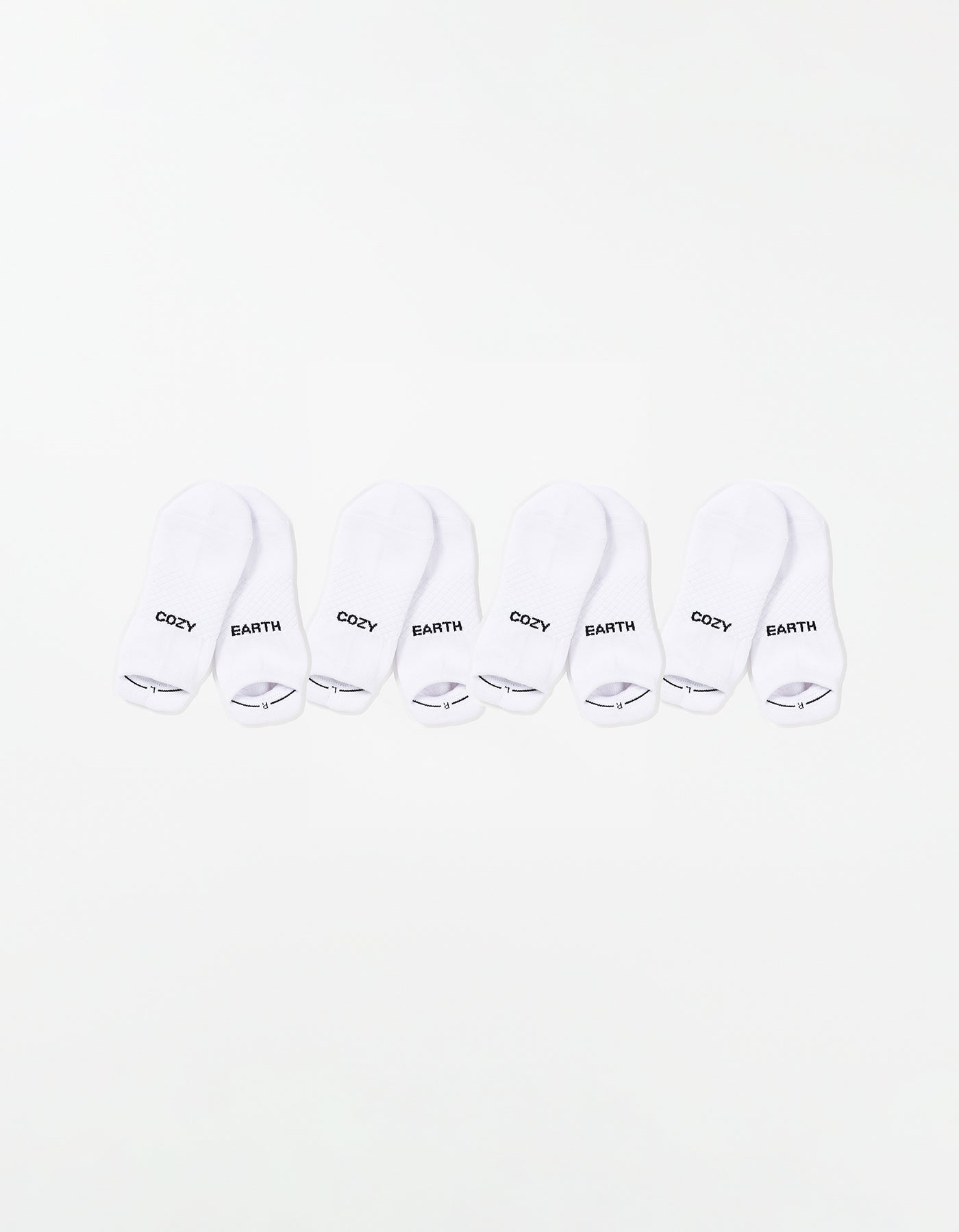 The Essential Ankle Sock 4-Pack by Cozy Earth features four pairs of white ankle socks, each with "COZY" and "EARTH" printed in black on top, arranged in a row on a white background. 