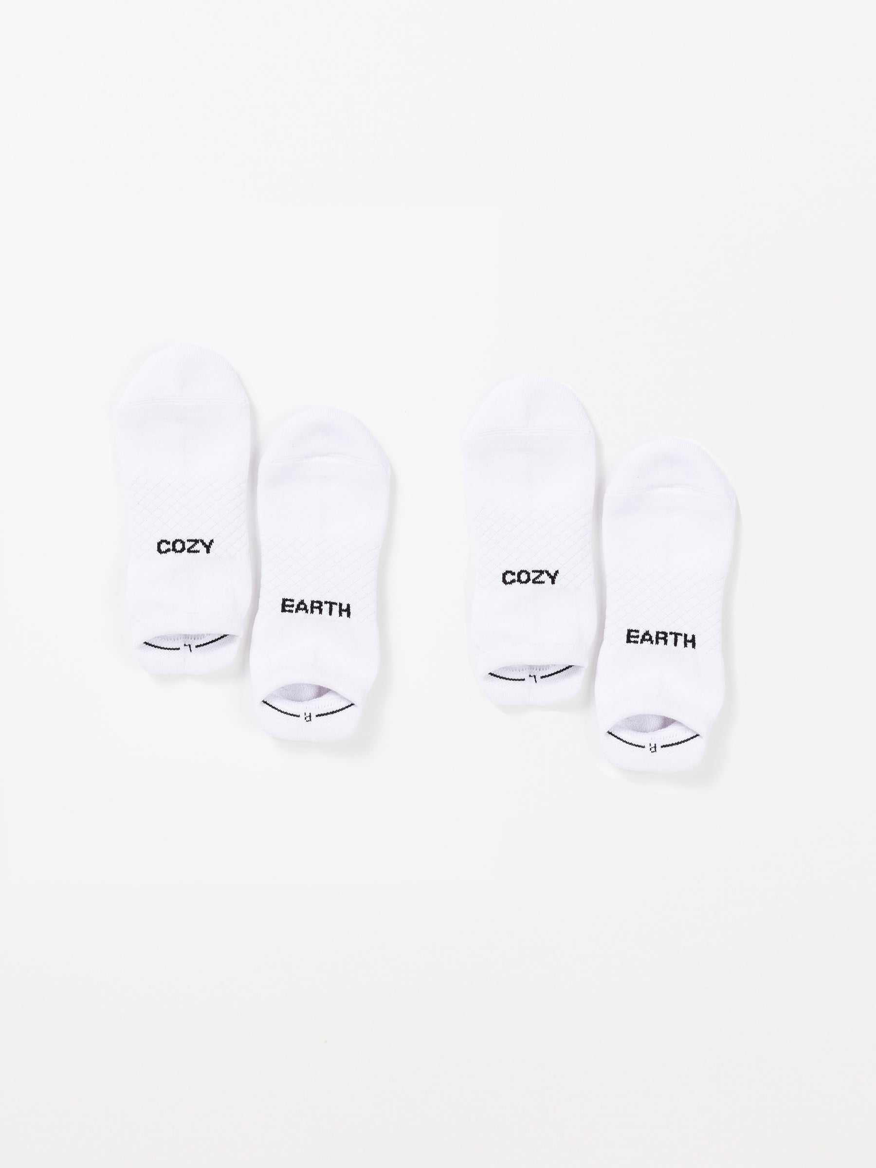 Two pairs of white Essential Ankle Socks from Cozy Earth are laid out on a plain background. The socks on the left have "COZY" written on the top and "EARTH" on the bottom. Similarly, the pair on the right features the same "COZY" and "EARTH" text. |Color:White|Count:2-Pack