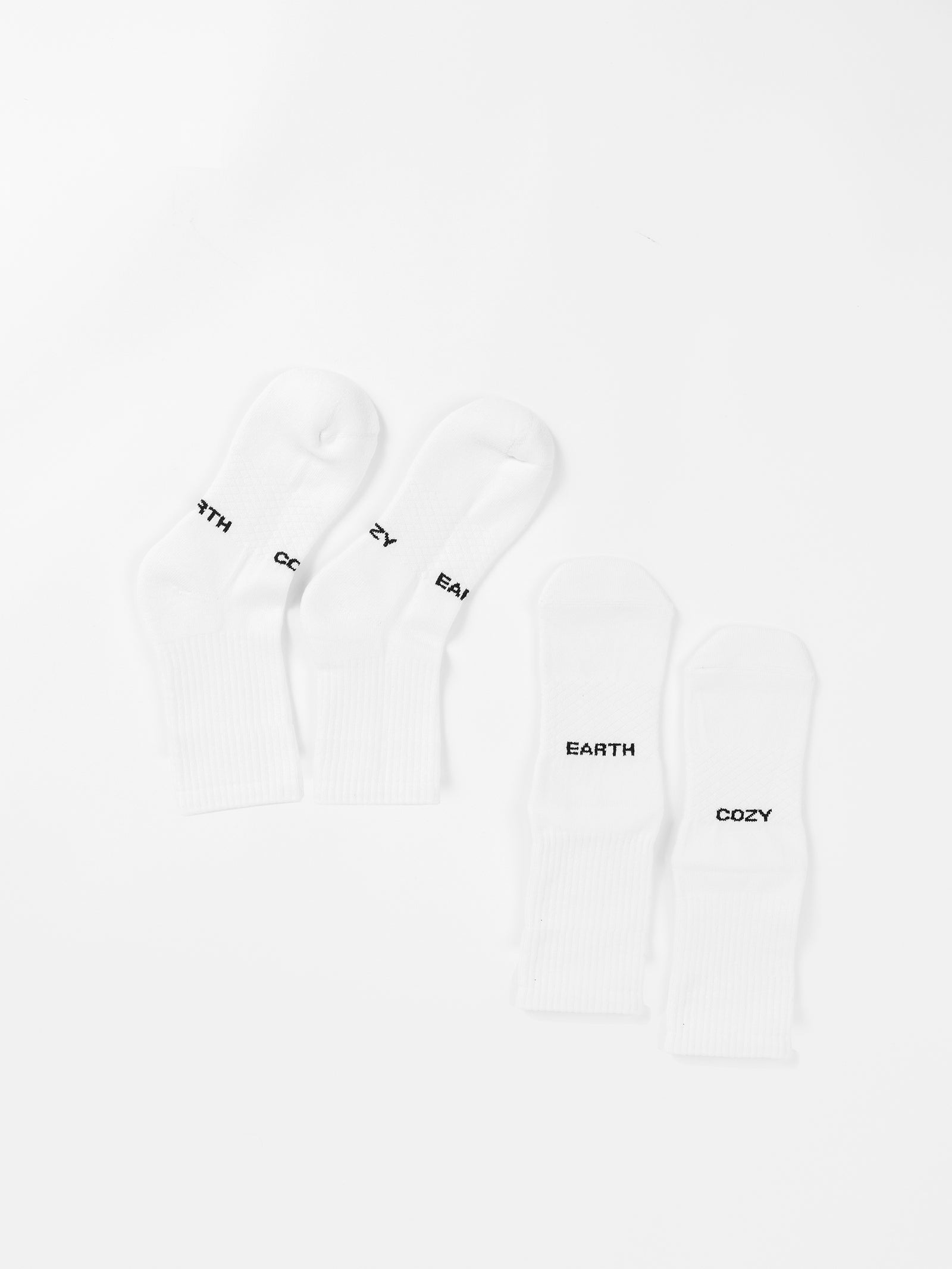 This image features the Cozy Earth Essential Calf Sock 2-Pack in white. One pair has "EARTH" and "COZY" written in black on each sock, while the other pair has the same words but on reversed socks. The socks are set against a plain white background. 