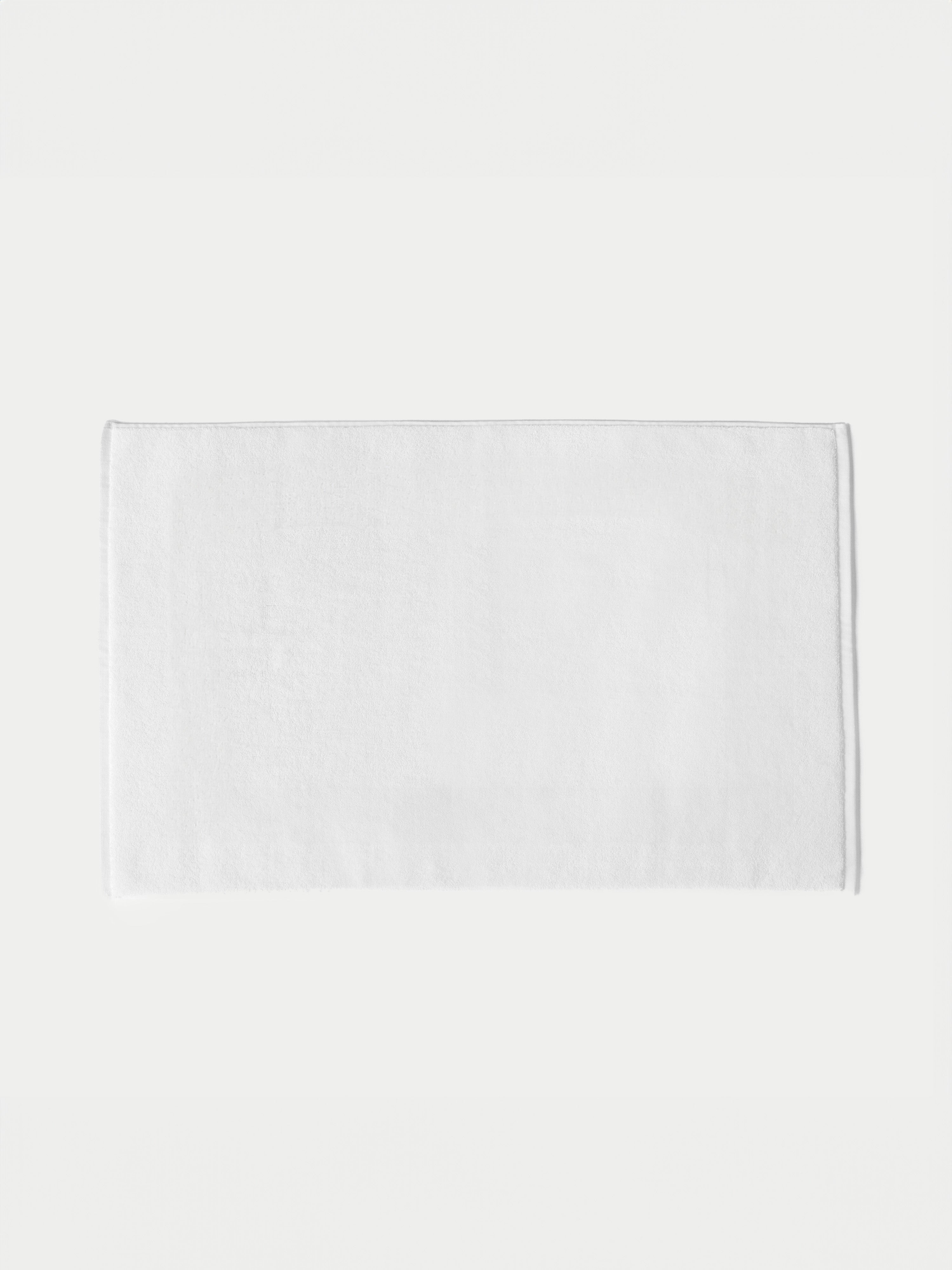 White looped terry bath mat resting on white background. |Color: White