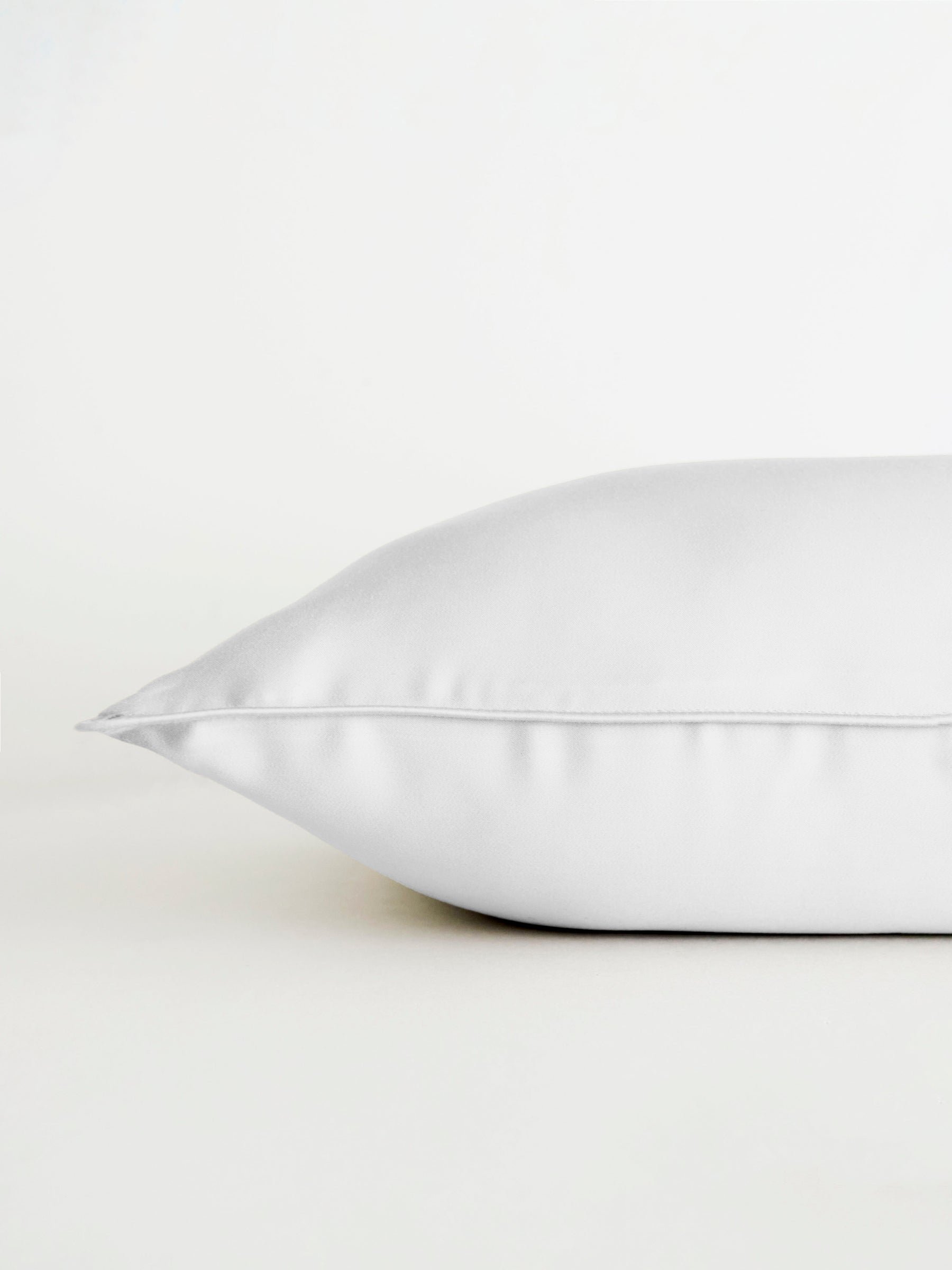 A Bamboo Travel Pillowcase by Cozy Earth is displayed on a white surface, side view against a plain white background, emphasizing its soft texture and smooth finish. 