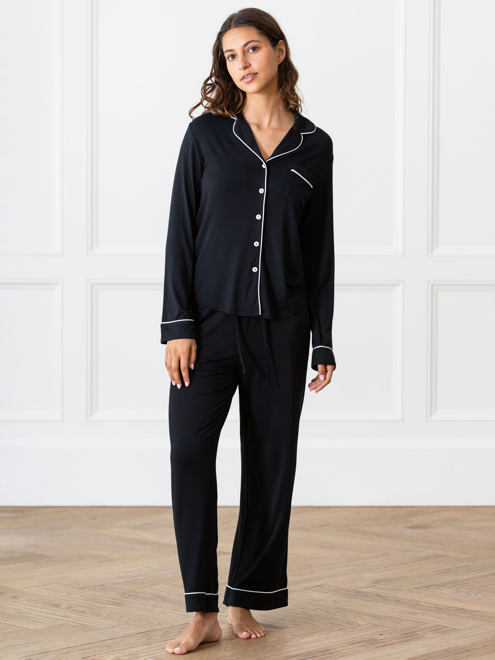 Black Long Sleeve Pajama Set modeled by a woman. The photo was taken in a light setting, showing off the colors and lines of the pajamas. 