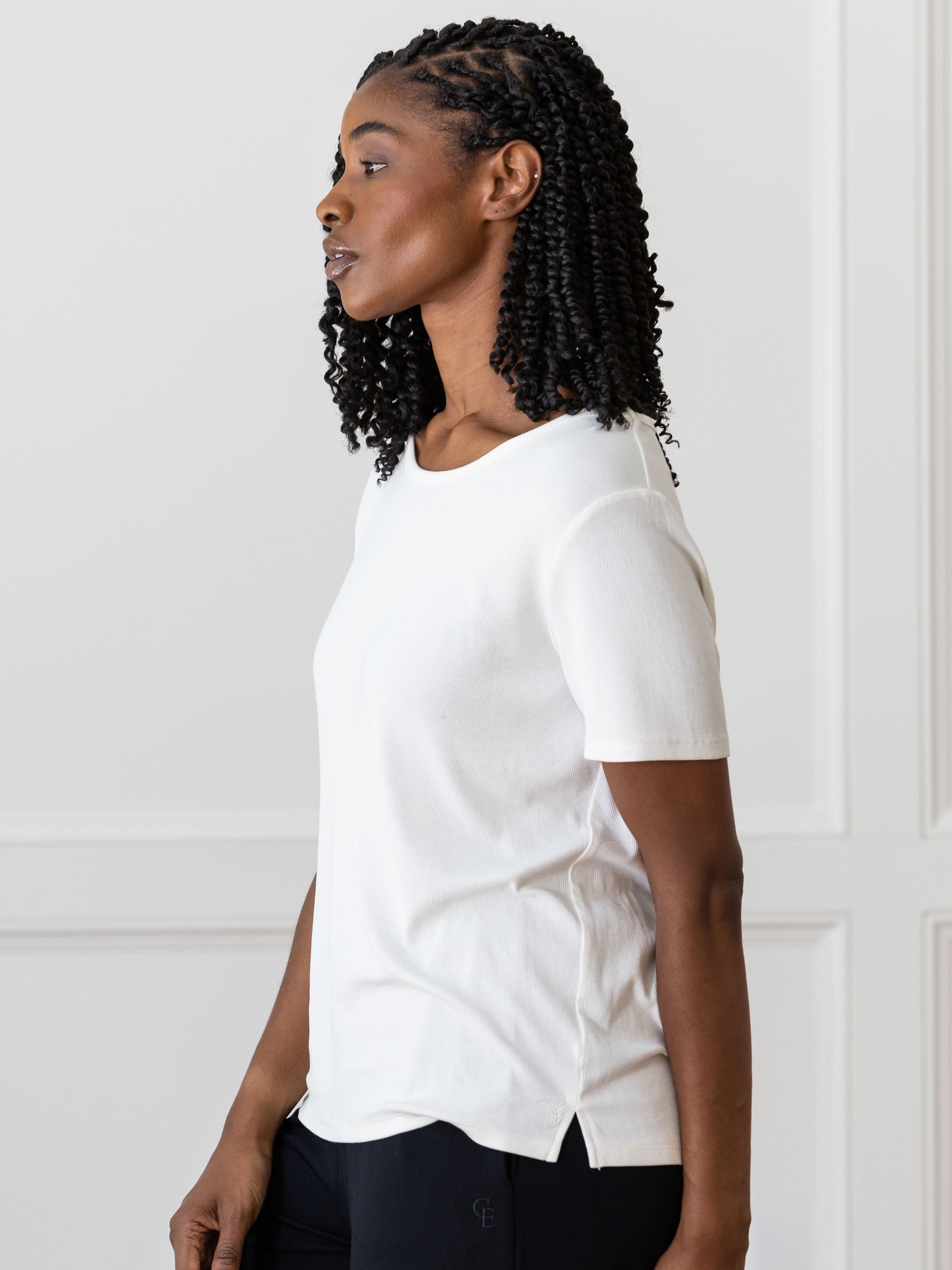 Woman wearing a white Cozy Earth Rib Knit Short Sleeve Lounge Top and black shorts against a white background 
