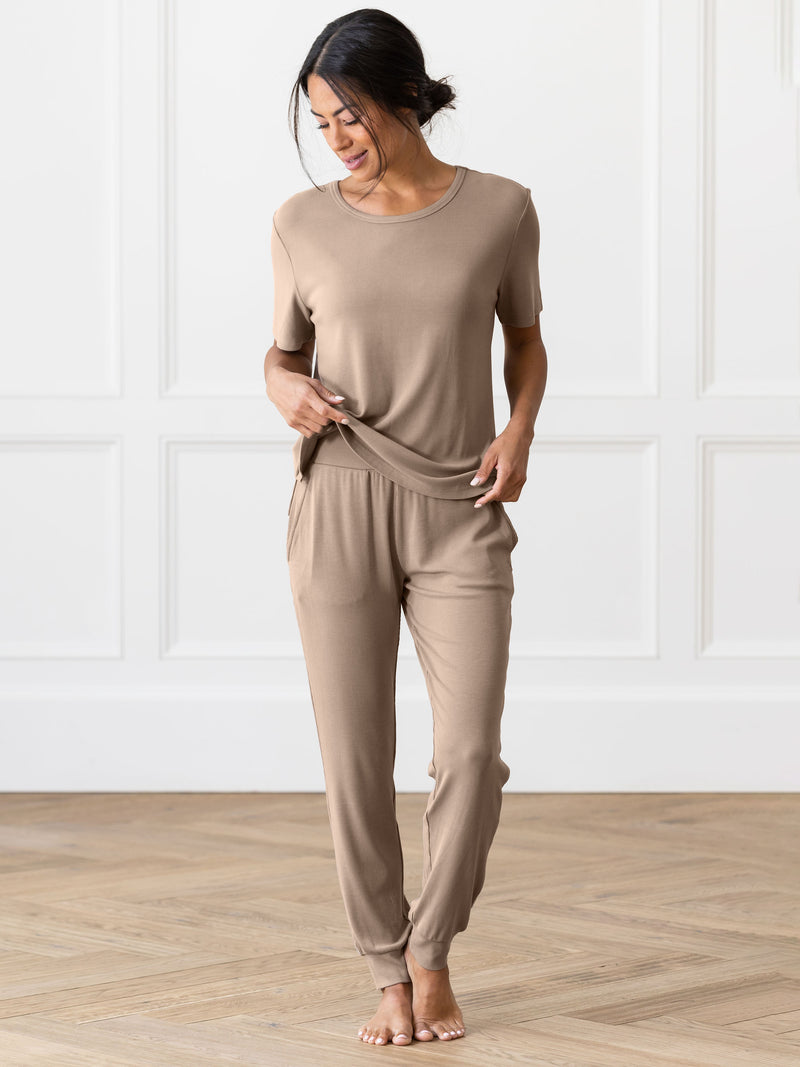 Person wearing beige Cozy Earth Rib Knit Joggers on a wooden floor with a white paneled wall background