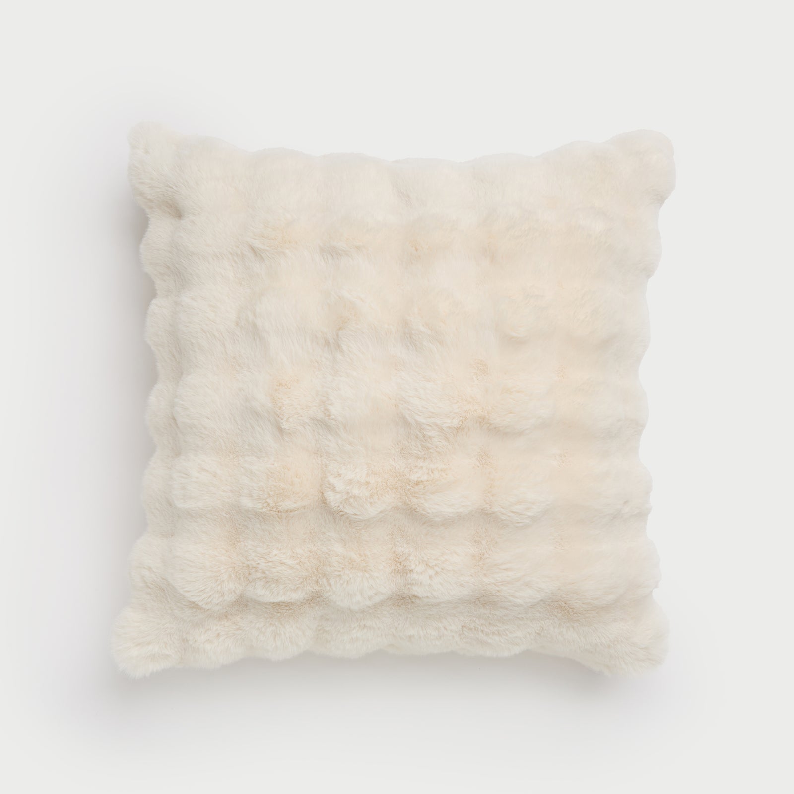 Introducing the Bubble Cuddle Pillow from Cozy Earth: a plush, cream-colored square pillow featuring a fluffy, textured surface. Its quilted design adds a touch of coziness against a simple white background. 