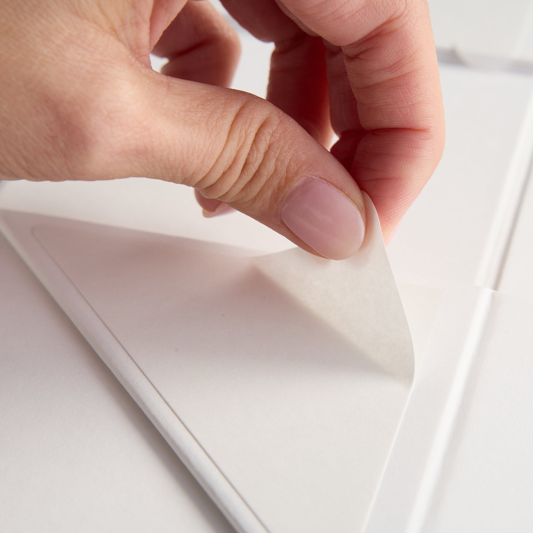 Hand pulling adhesive strip off gift box 