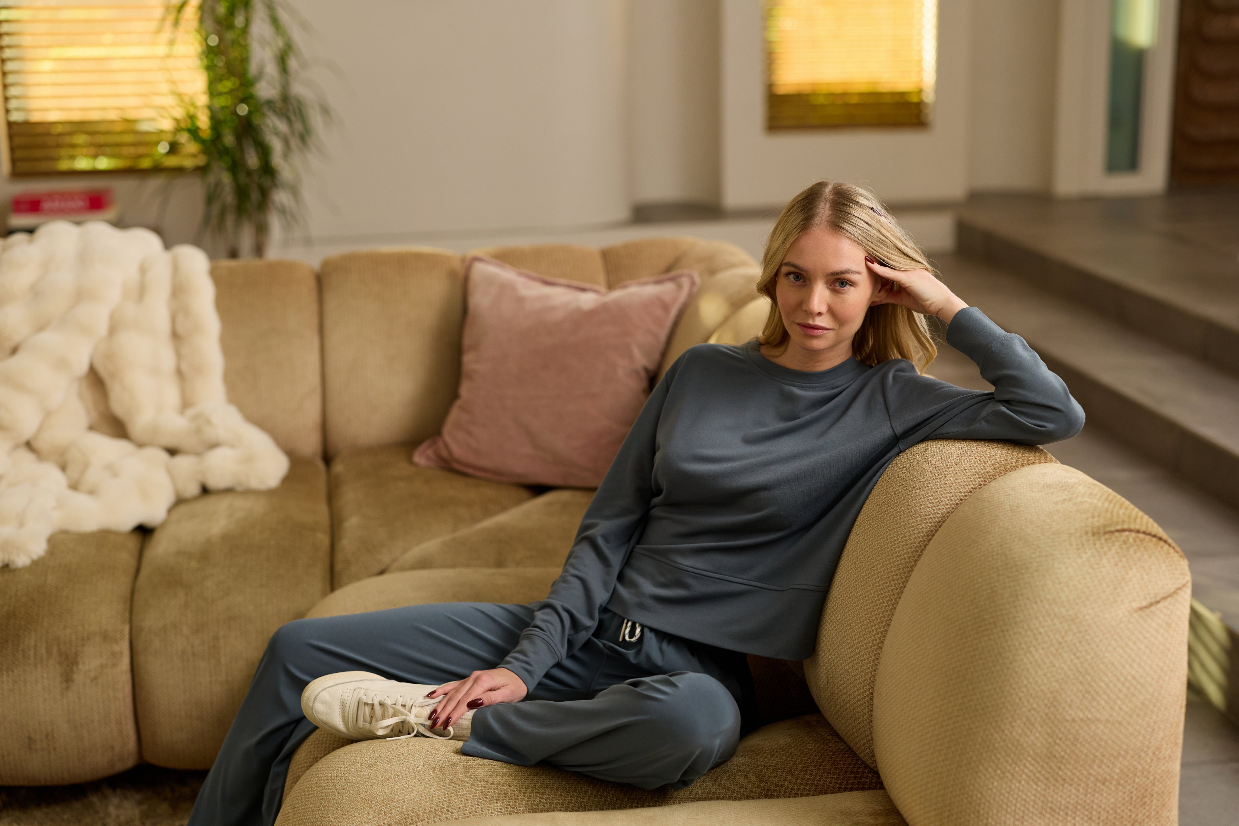 Woman sitting on a beige couch in a living room setting