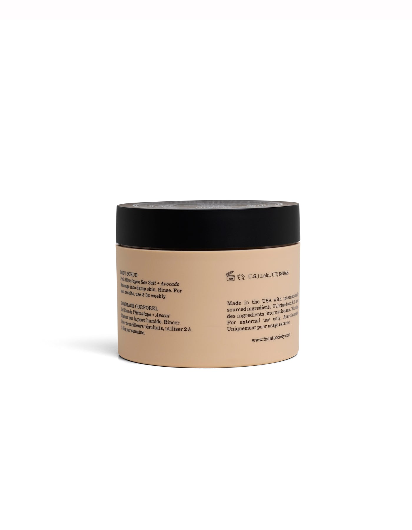 A beige Cozy Earth Body Scrub jar with black lid displays its back label—usage instructions, ingredients, and manufacturing details in black text—set against a plain white background.