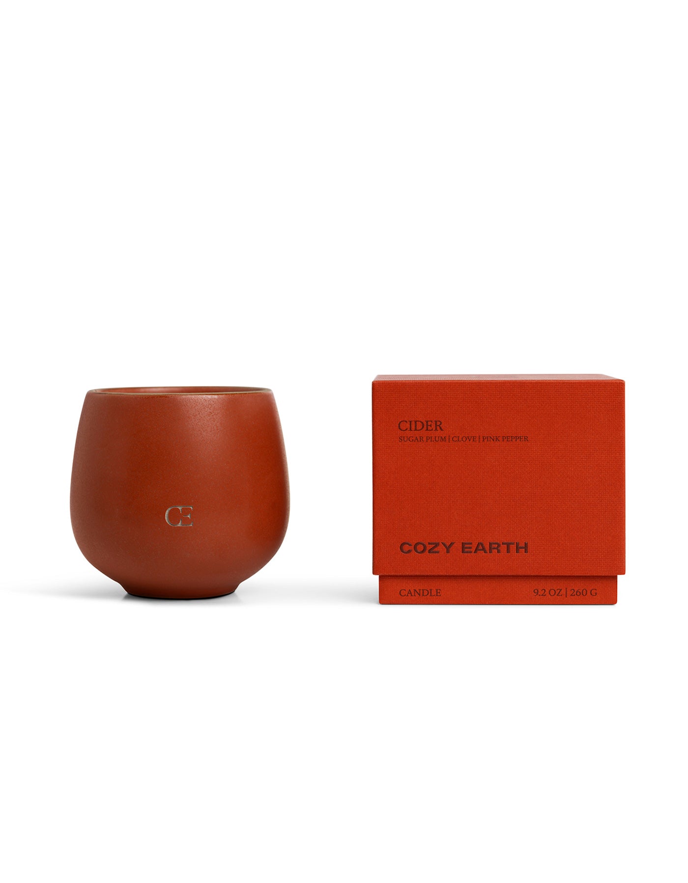 The Candle CIDER by Cozy Earth is a brown candle in a round holder, paired with a matching box labeled "COZY EARTH" and "Cider," featuring scent notes of cedar, sugar plum, clove, and pink pepper.