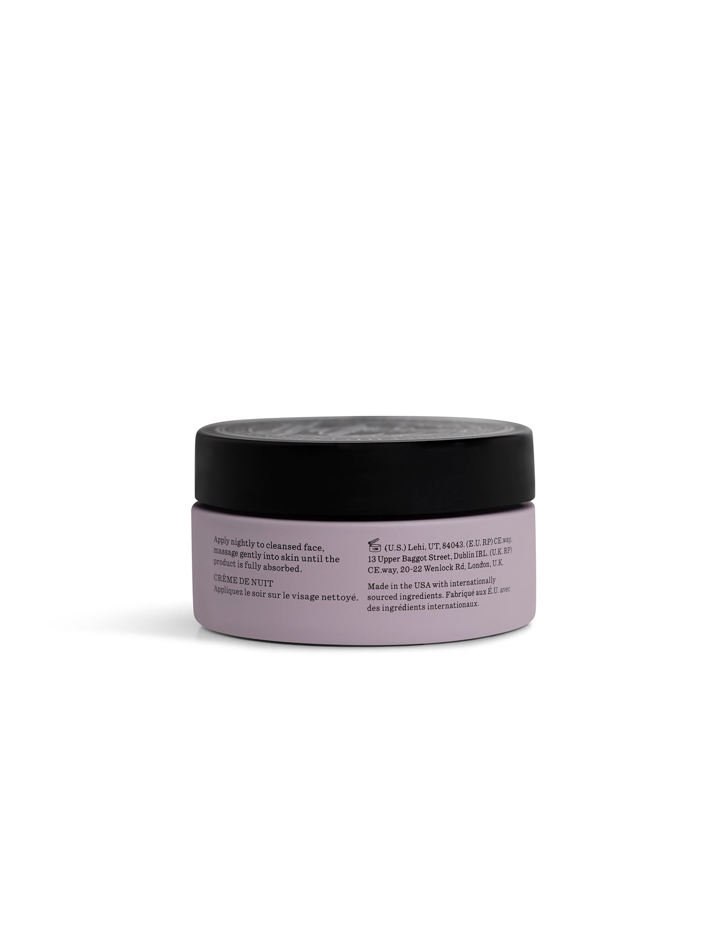 A small, round, lavender-colored jar of Cozy Earth Day-to-Night Essentials with a black lid is shown from the back, displaying label text instructions and product details against a plain white background.