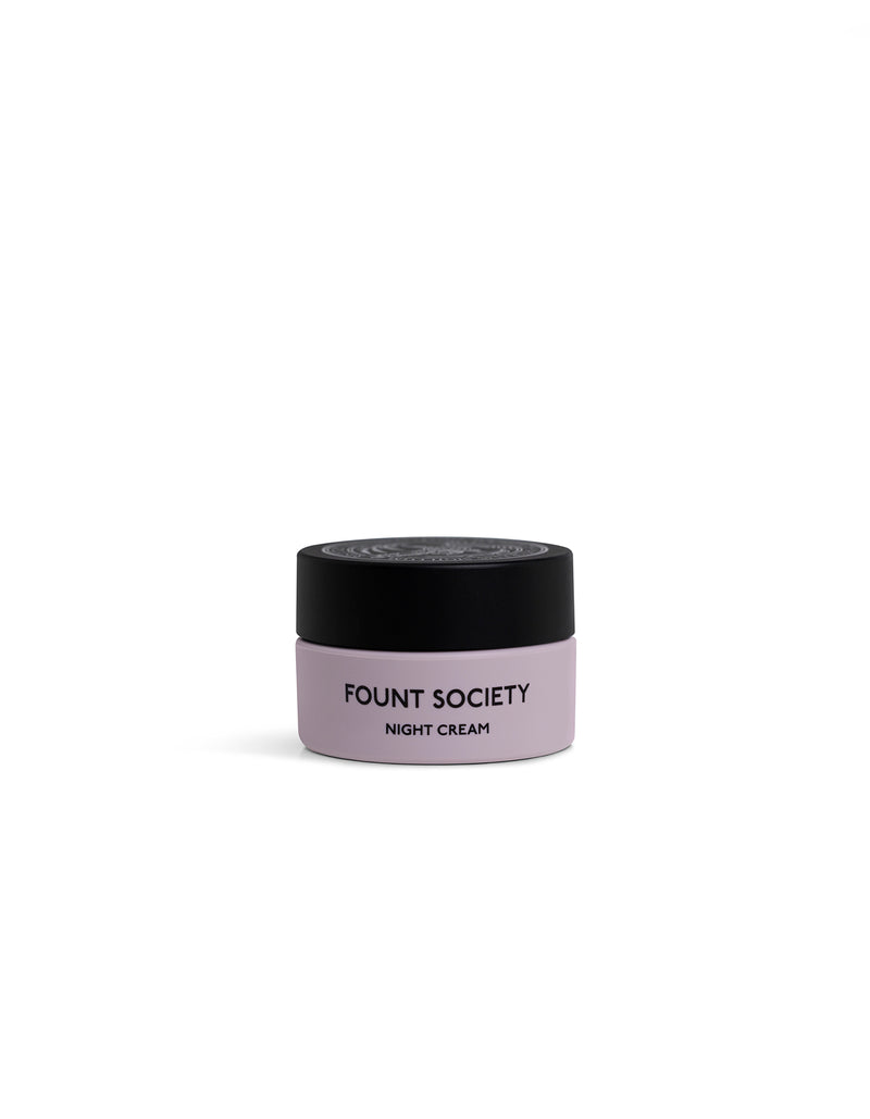 A small, round jar of Cozy Earth Night Cream with a light purple body and black lid is displayed against a plain white background.