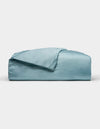 A neatly folded Cozy Earth Bamboo Duvet Cover in light blue, with one corner draped over the top, displayed against a plain white background.|Color:River