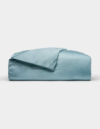 A neatly folded Cozy Earth Bamboo Duvet Cover in light blue, with one corner draped over the top, displayed against a plain white background.|Color:River