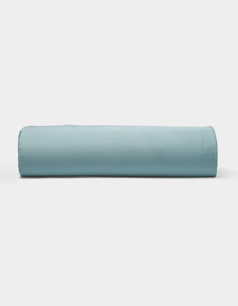 A neatly rolled light blue Bamboo Sheet Set by Cozy Earth is displayed on a plain white background.