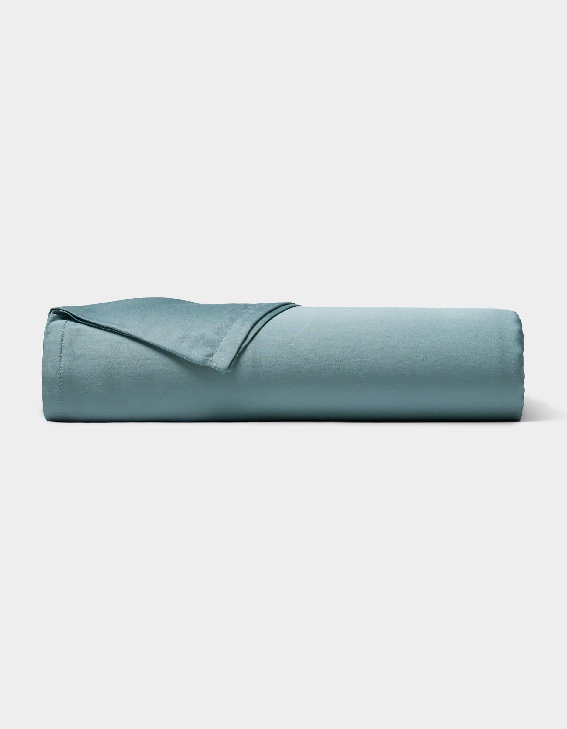 A neatly rolled Bamboo Sheet Set by Cozy Earth in light blue is displayed on a plain white background.|Color:River