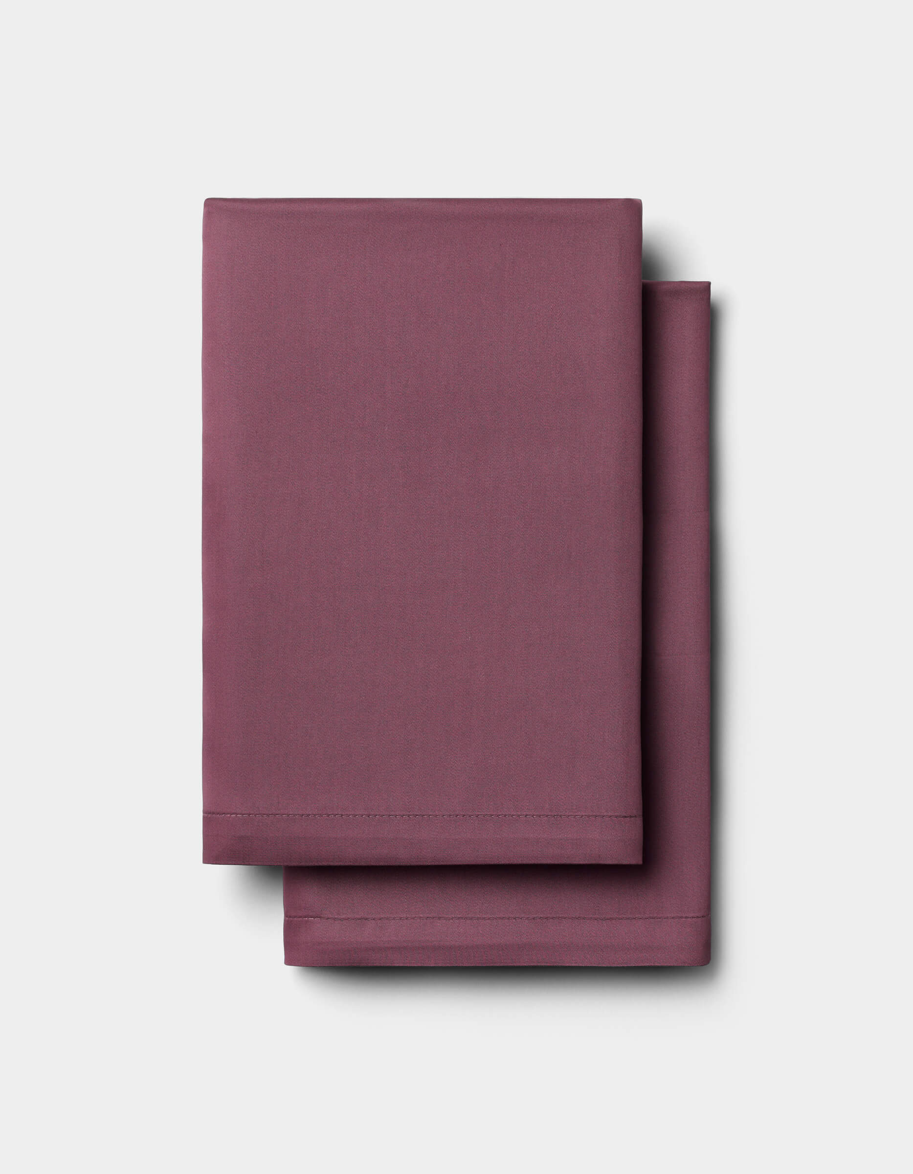 Two neatly folded Cozy Earth Bamboo Sheet Sets in solid mauve or plum, stacked against a plain light gray background.|Color:Mulberry