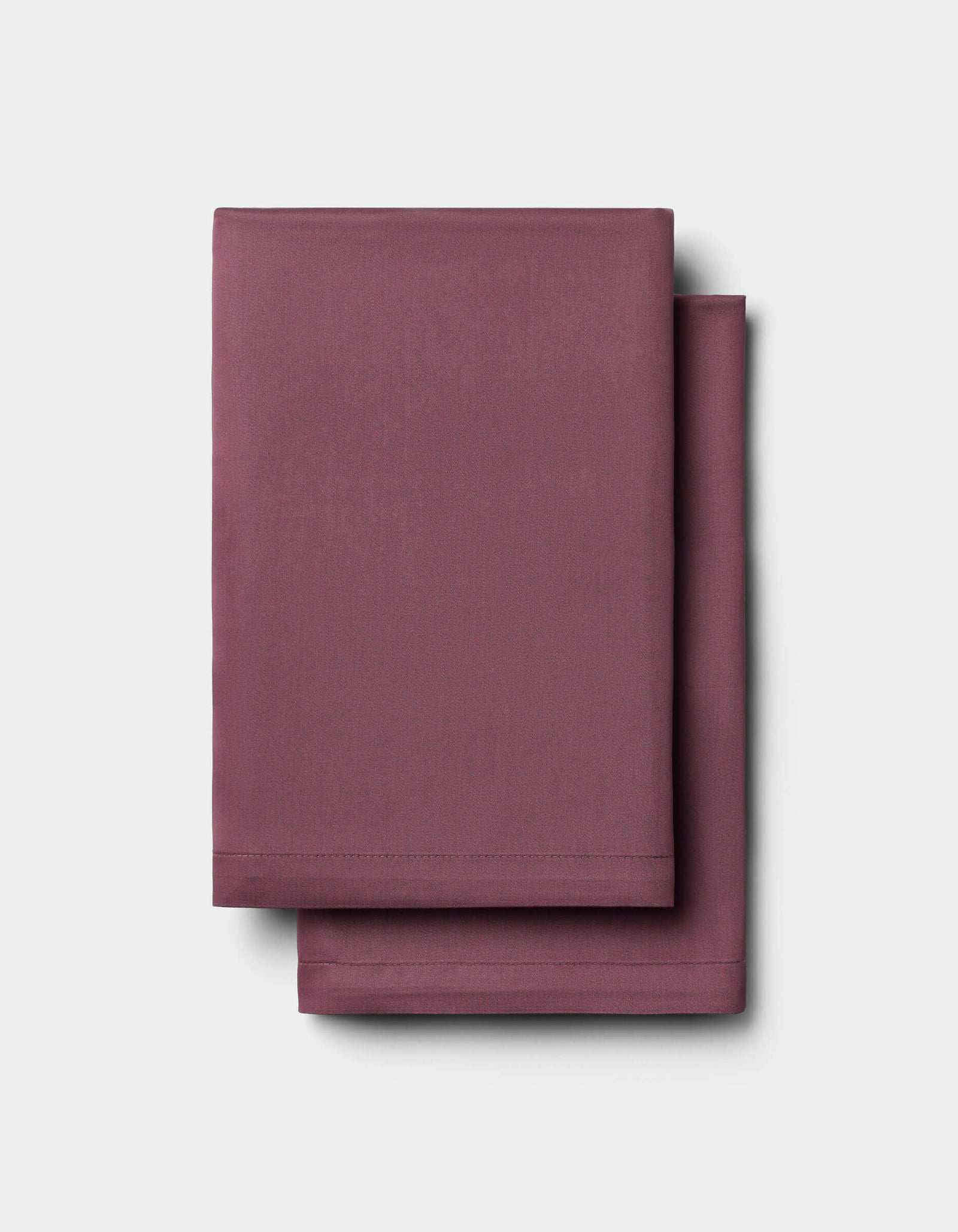 Two neatly folded Cozy Earth Bamboo Pillowcases in solid mauve are stacked atop each other against a plain light gray background.
