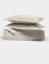 Two cream-colored pillows from Cozy Earth's Bamboo Quilt Bundle are stacked atop a neatly folded matching quilt, all displayed against a plain white background.|Color:Oat