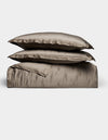 The Cozy Earth Bamboo Quilt Bundle features two plush pillows and a folded, shiny taupe duvet, all neatly arranged against a plain white background.|Color:Walnut