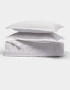 The Cozy Earth Bamboo Quilt Bundle features two fluffy white pillows stacked on a neatly folded white comforter, all shown against a plain white background.|Color:White