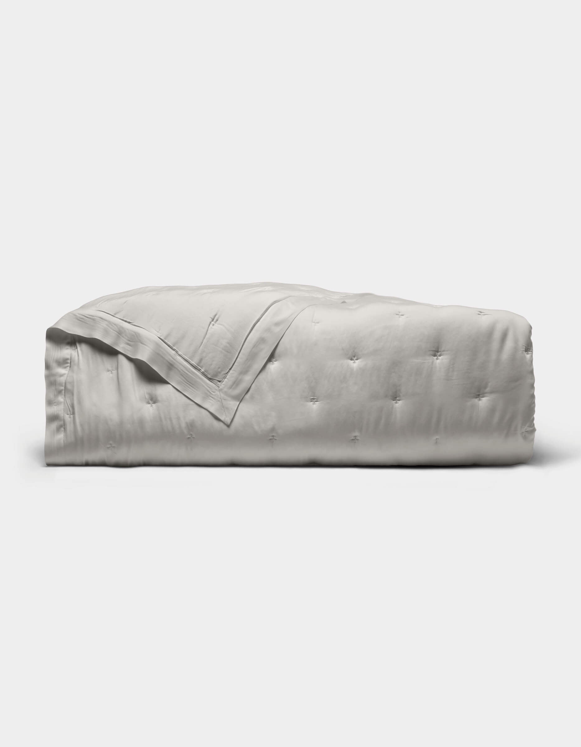 The Cozy Earth Bamboo Quilt, featuring a subtle tufted pattern and light gray color, is neatly folded against a plain white background.|Color:Light Grey