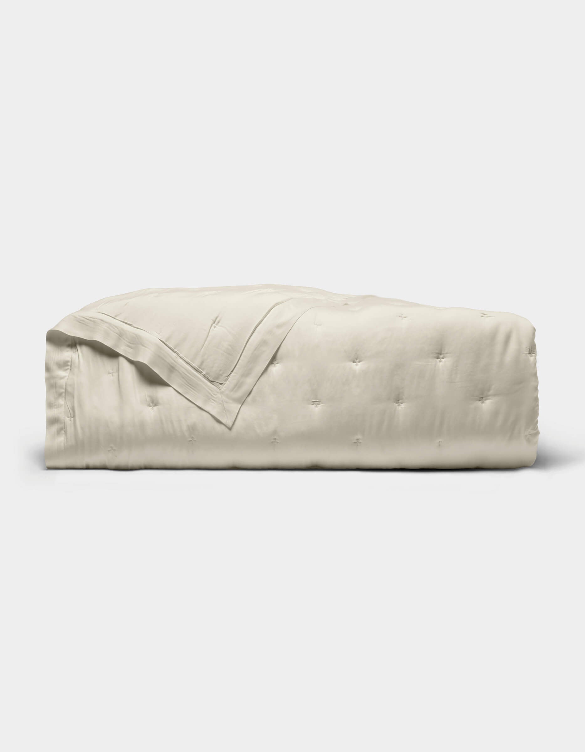 The Cozy Earth Bamboo Quilt, featuring a subtle quilted pattern and light beige color, is neatly folded and displayed against a plain white background.|Color:Oat