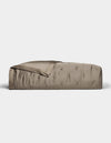 A neatly made bed with a smooth, shiny taupe Cozy Earth Bamboo Quilt and matching blanket partially folded back, set against a plain white background.|Color:Walnut