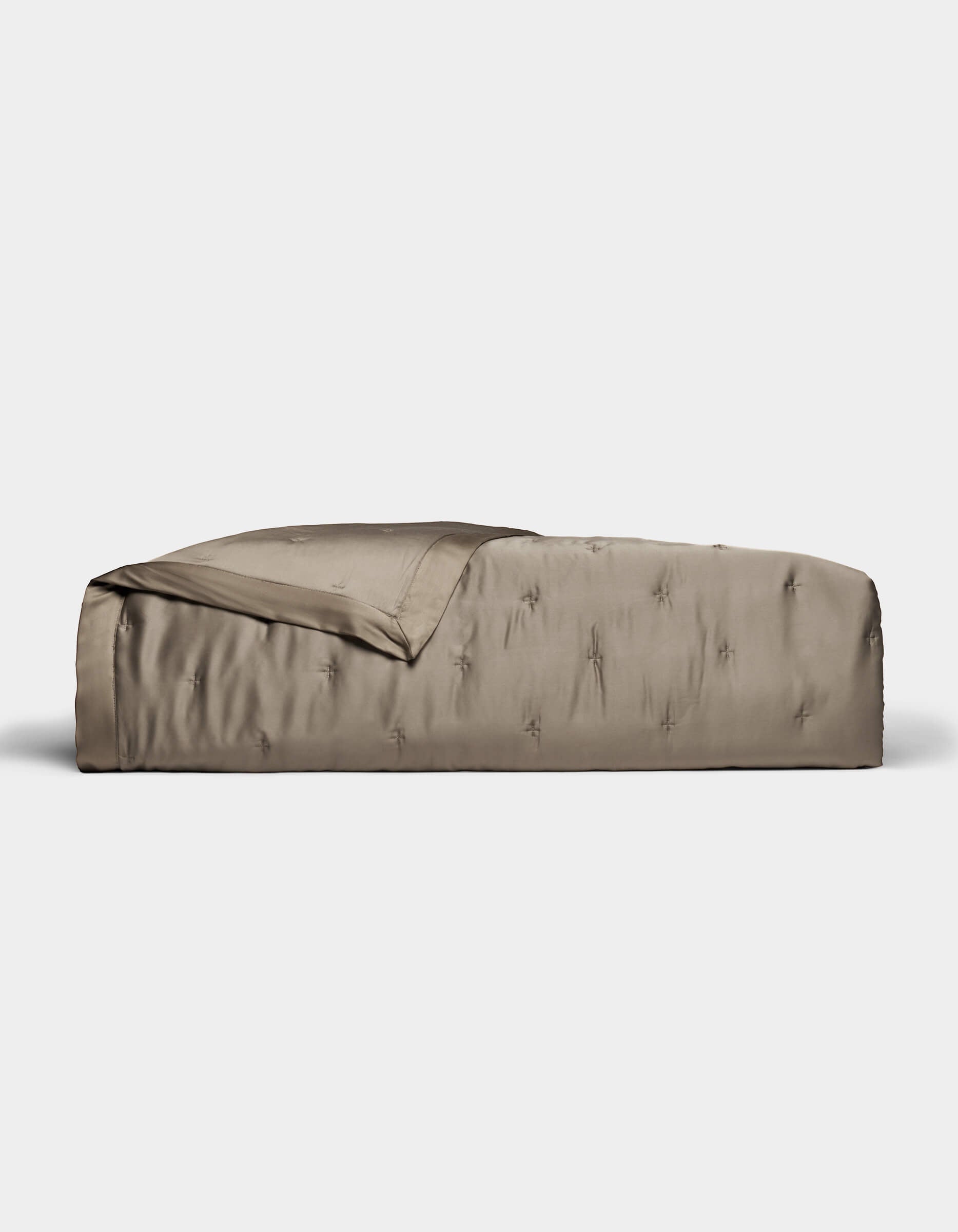 A neatly made bed with a smooth, shiny taupe Cozy Earth Bamboo Quilt and matching blanket partially folded back, set against a plain white background.|Color:Walnut