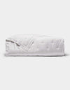 The Cozy Earth Bamboo Quilt is a neatly folded white quilt with a subtle quilted pattern, displayed against a plain light gray background.|Color:White