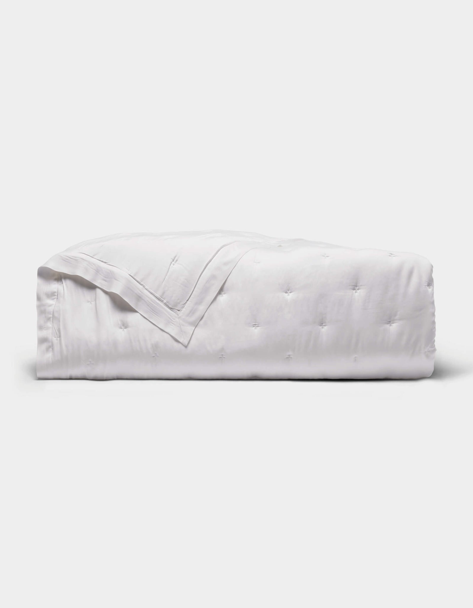 The Cozy Earth Bamboo Quilt is a neatly folded white quilt with a subtle quilted pattern, displayed against a plain light gray background.