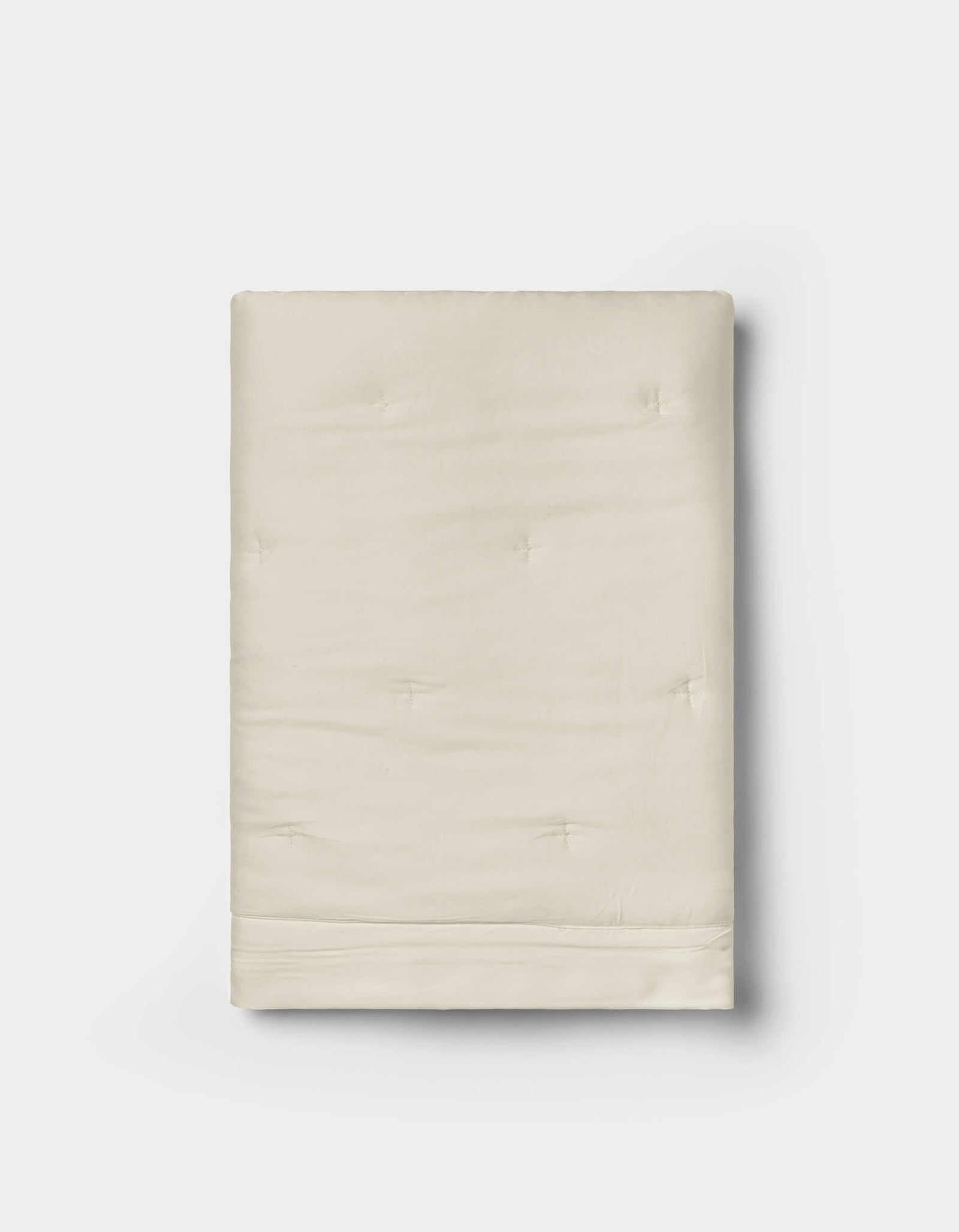A pair of folded, cream-colored Bamboo Quilted Shams by Cozy Earth, featuring a smooth texture and subtle tufted details, displayed on a white background.