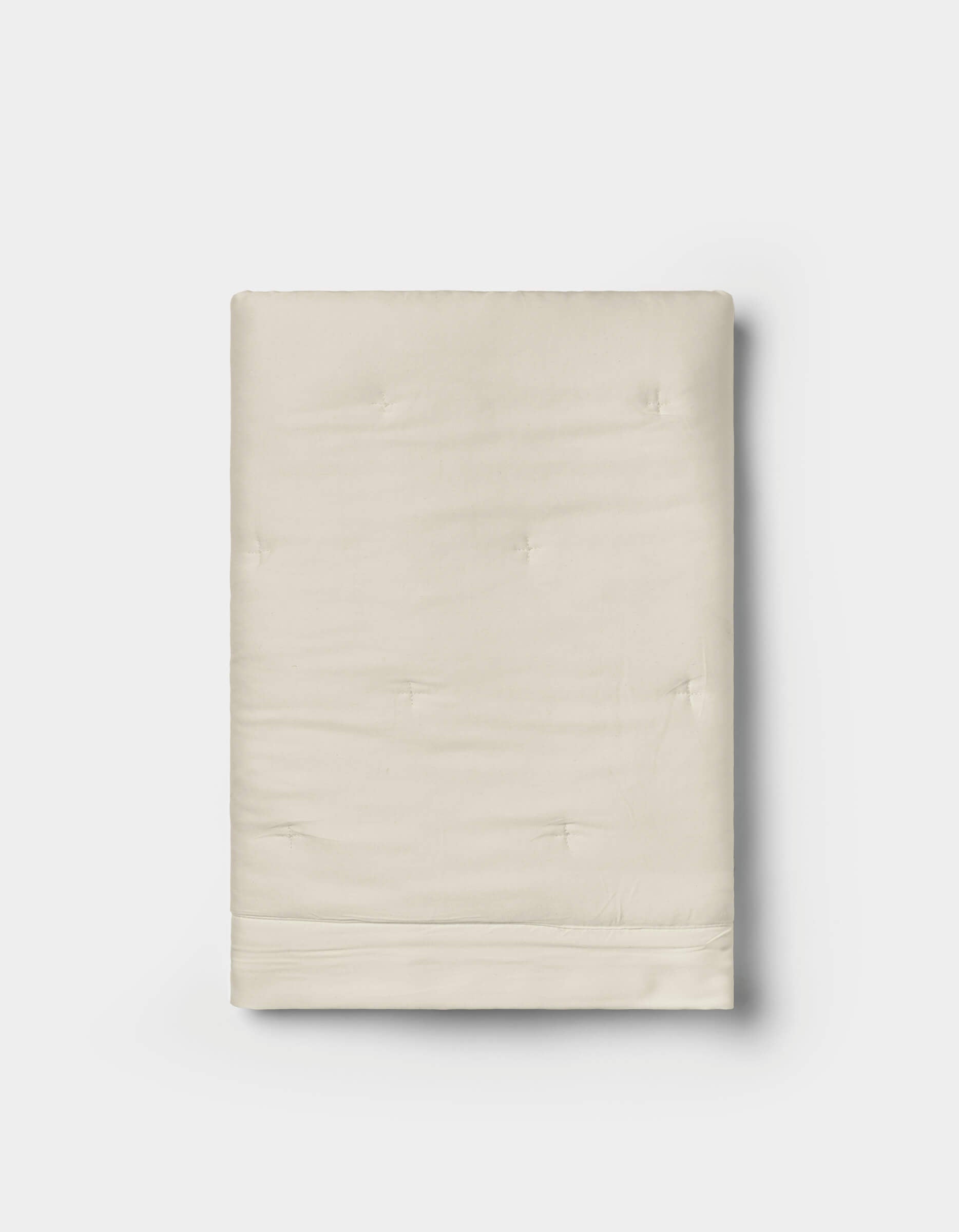 A pair of folded, cream-colored Bamboo Quilted Shams by Cozy Earth, featuring a smooth texture and subtle tufted details, displayed on a white background.