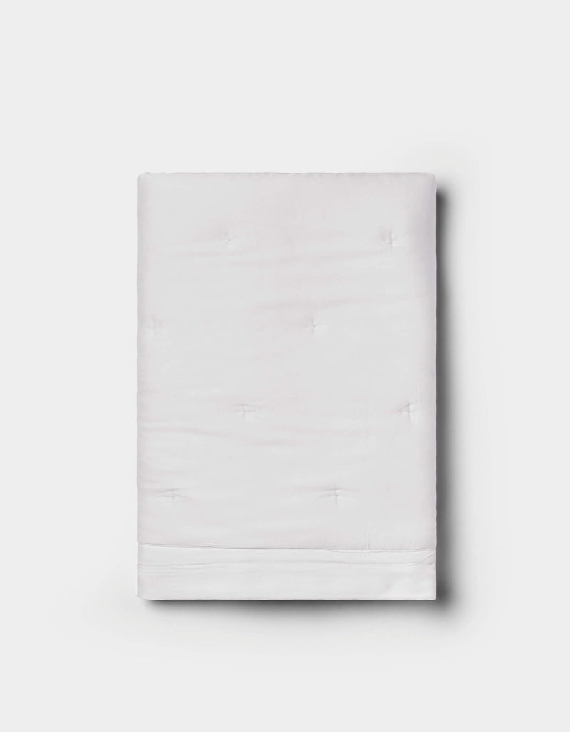 The Bamboo Quilted Shams by Cozy Earth are neatly folded, featuring a subtle quilted texture in white, displayed against a plain light gray background.