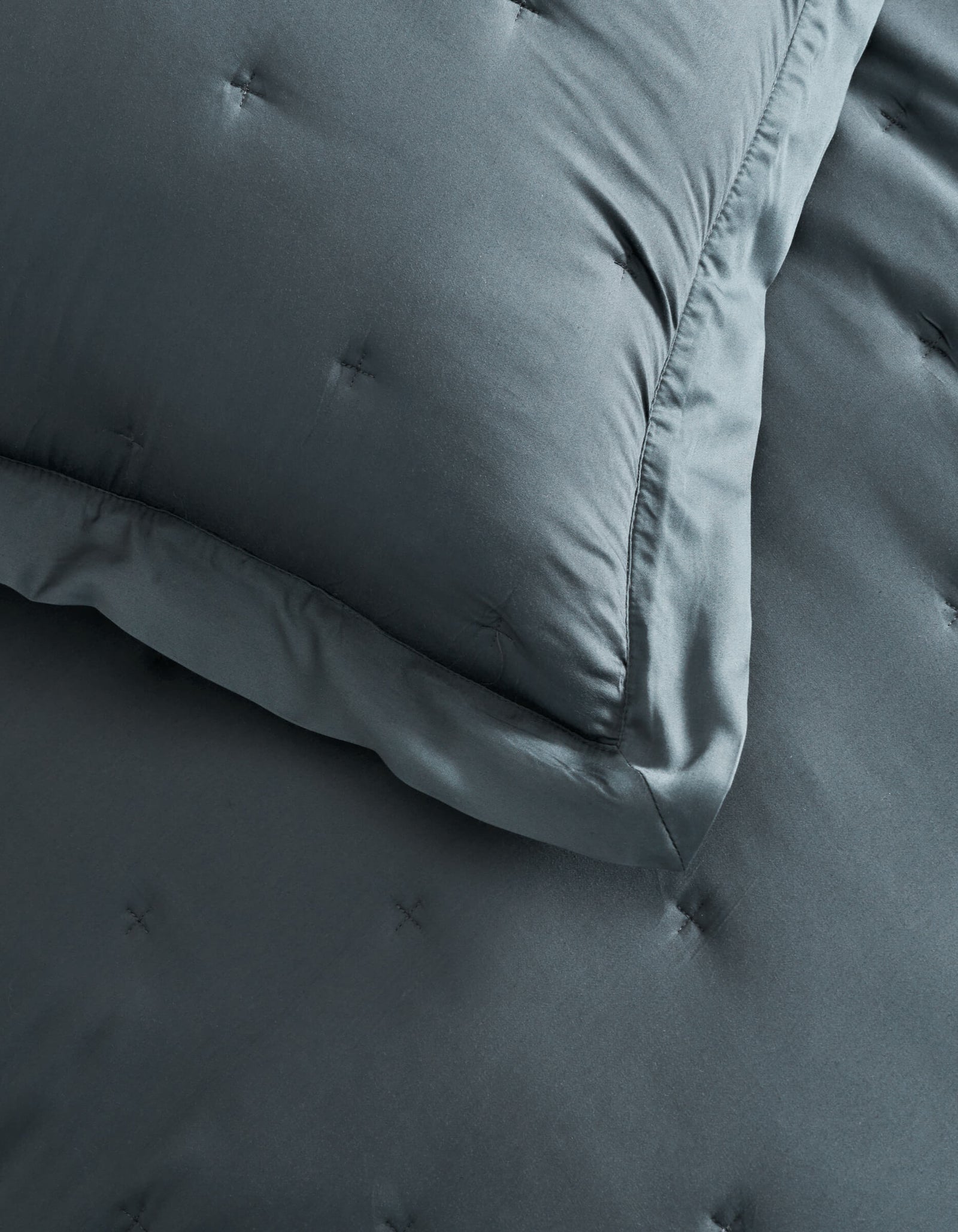 A close-up of a neatly made bed featuring Cozy Earth Bamboo Quilted Shams in dark gray, each with small tufted stitches.