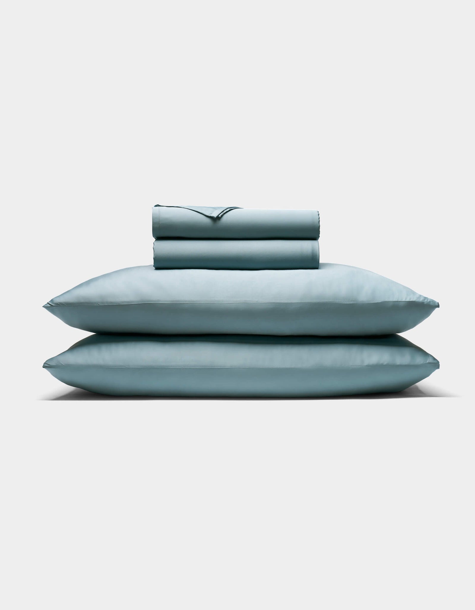 The Cozy Earth Bamboo Sheet Set, featuring two pillows and a folded sheet in pale blue, is neatly stacked against a plain white background.