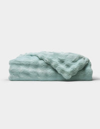 The Bubble Cuddle Blanket by Cozy Earth, in a soft light blue, is shown folded neatly on a white background.|Color:Tide