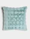 The Bubble Cuddle Pillow by Cozy Earth is a square, light blue faux fur pillow with a plush, textured surface and wavy scalloped edges, shown against a white background.|Color:Tide |Size:Euro