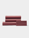The Cozy Earth Bamboo Bedding Core Bundle, featuring four folded reddish-brown bed sheets and two matching pillowcases, is neatly stacked against a plain white background.|Color:Mulberry