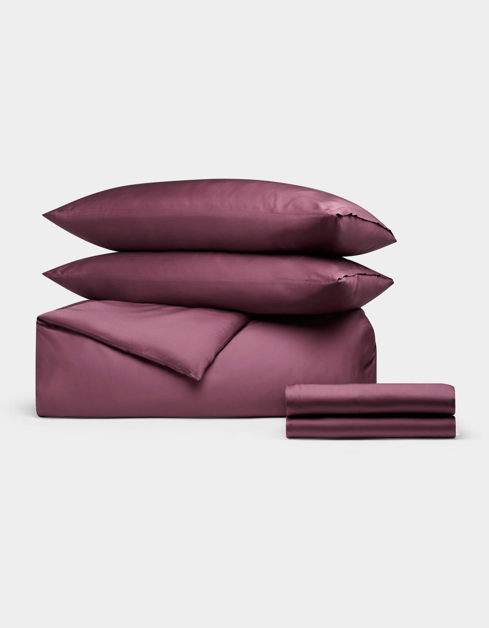 The Cozy Earth Bamboo Bedding Deluxe Bundle features rich mulberry set with two stacked pillows, a comforter, and folded sheets, elegantly displayed against a plain light background.