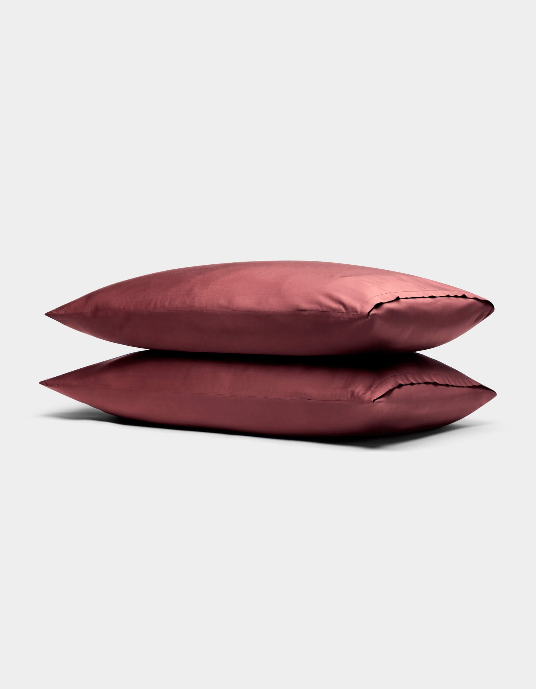 Two stacked, smooth, rose-colored Cozy Earth Bamboo Pillowcases are displayed on a neutral light gray background.|Color:Mulberry