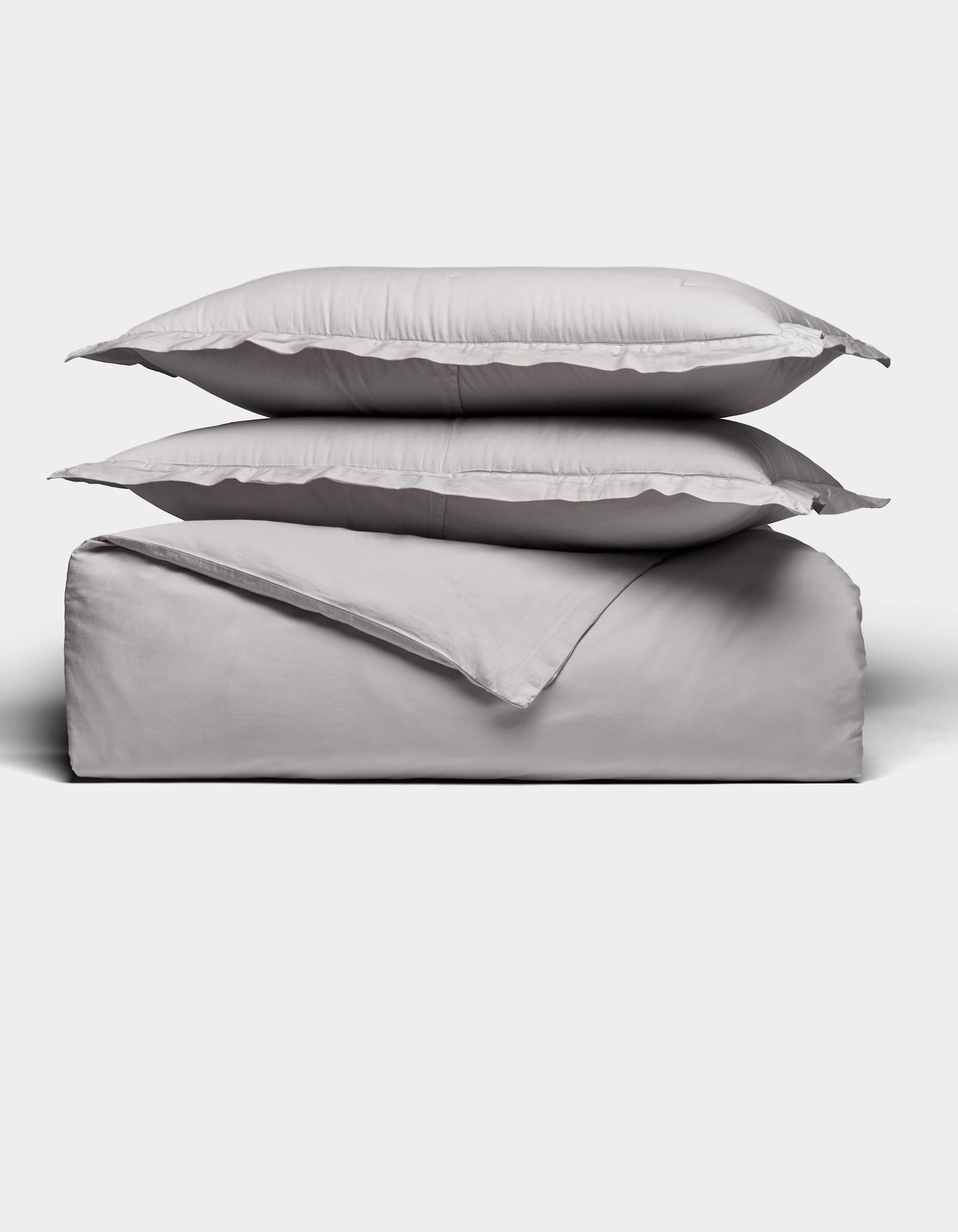 Two gray pillows rest atop a folded Soft-Wash Cotton Duvet Set by Cozy Earth, all neatly arranged against a plain white background.