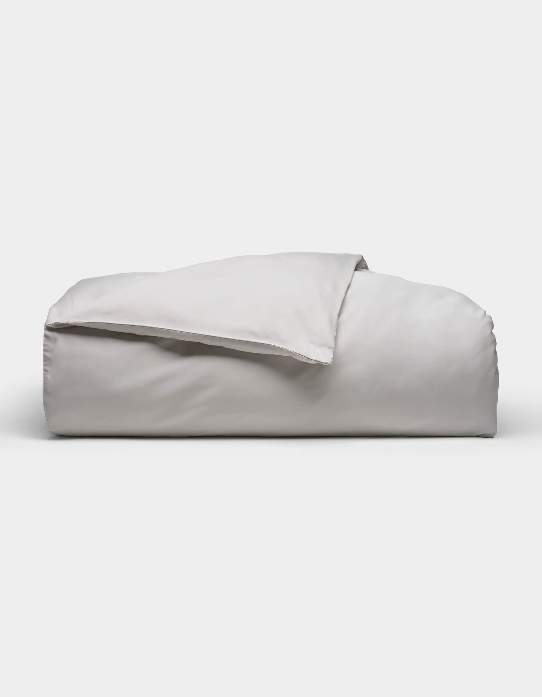 The Soft-Wash Cotton Duvet Cover by Cozy Earth, shown neatly folded in light gray with a smooth, soft texture, is displayed against a plain white background.|Color:Dew