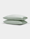 Two Cozy Earth Soft-Wash Cotton Pillowcases in light green are neatly stacked against a plain white background.|Color:Laurel