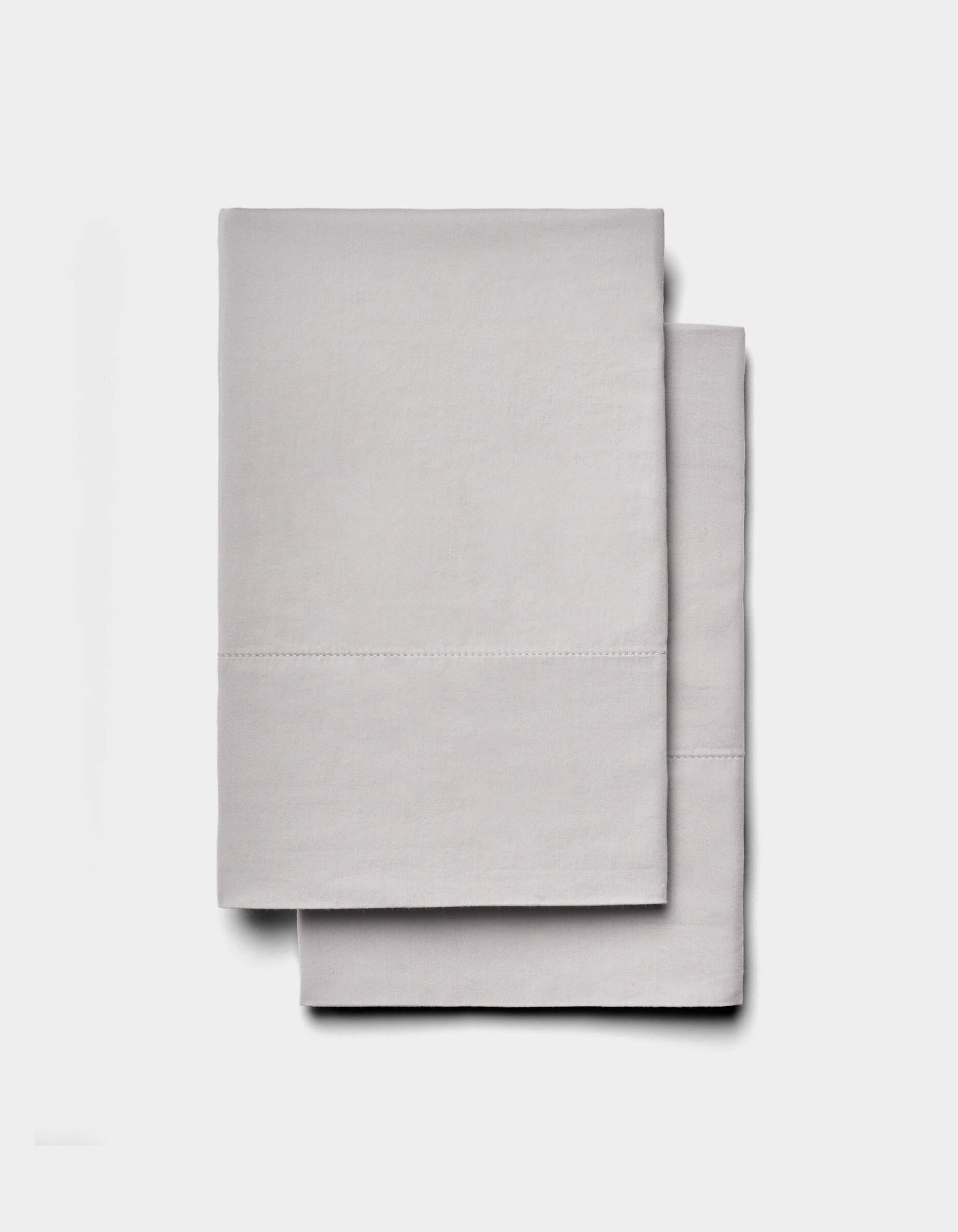 Two neatly folded Soft-Wash Cotton Sheet Sets by Cozy Earth in light gray are stacked on a plain white background.