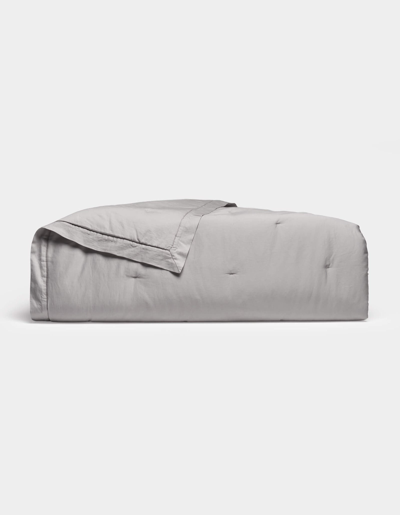 The Cozy Earth Soft-Wash Cotton Quilt in light gray features a subtle quilted pattern and is neatly folded, displayed against a plain white background.