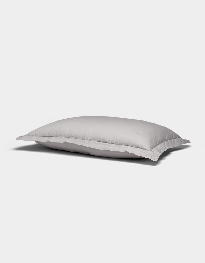 A Soft-Wash Cotton Quilted Sham by Cozy Earth, white and rectangular with a smooth surface, rests on a plain light gray background.