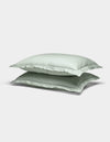 Two Soft-Wash Cotton Shams by Cozy Earth in light green are stacked atop each other against a plain white background.|Color:Laurel